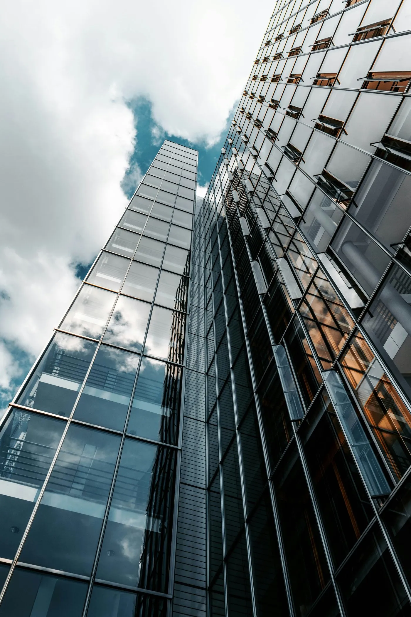 Looking up at a glass office tower against a cloudy sky