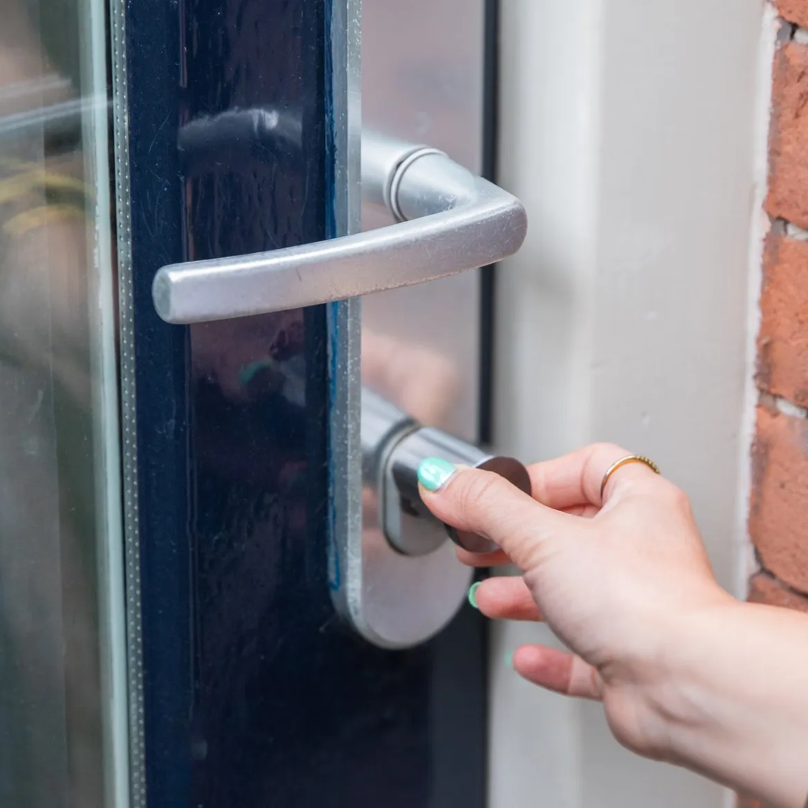 A hand turning the outside knob of a Bold lock on a front door
