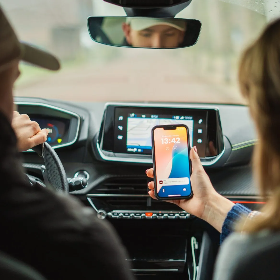 A passenger in a car, reading a notification on their phone