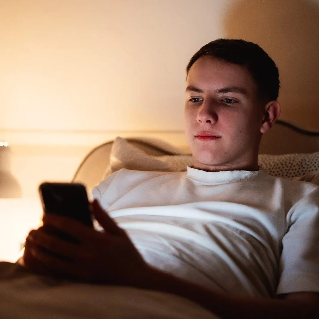 Someone in bed at night, checking their phone