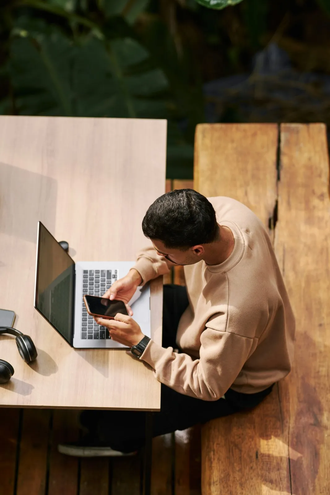 Someone at a sunny outdoor table with a laptop, using the Bold app on their phone