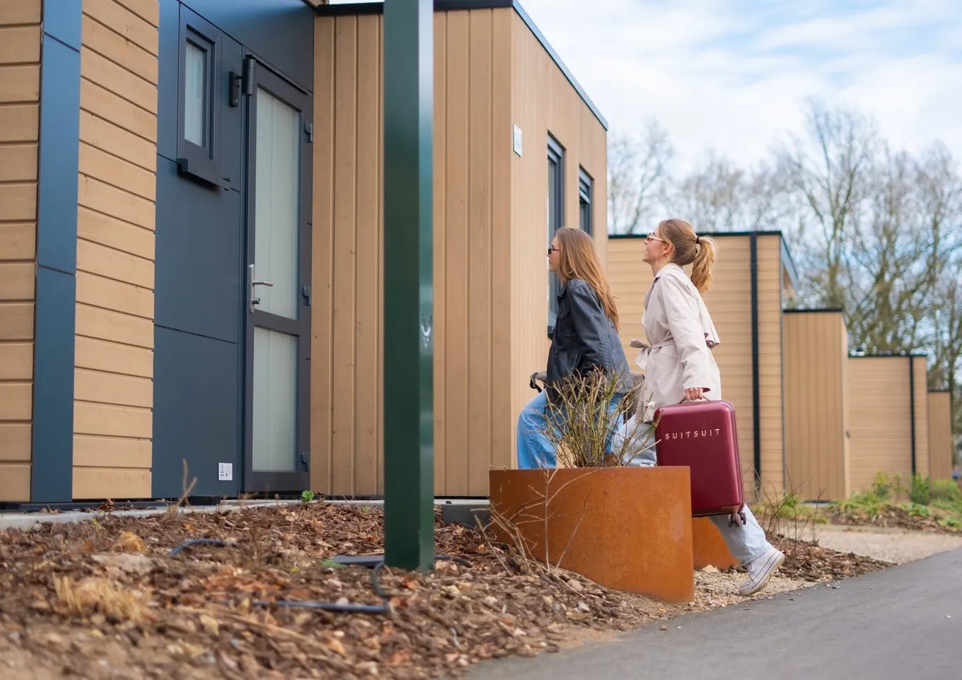Twee gasten met een koffer die aankomen bij een vakantiehuis